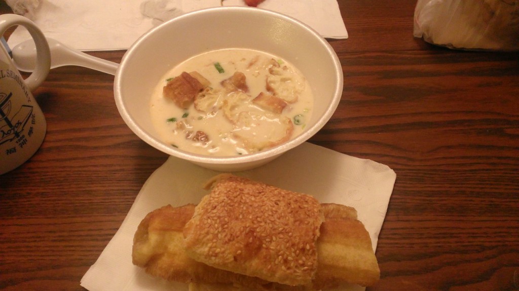 Hot unsweetened soy milk, mixed with salty/pickled goodness, and a bread sandwich to dip. It is fried dough sandwiched within a toasted sesame seed bread. Seriously good.